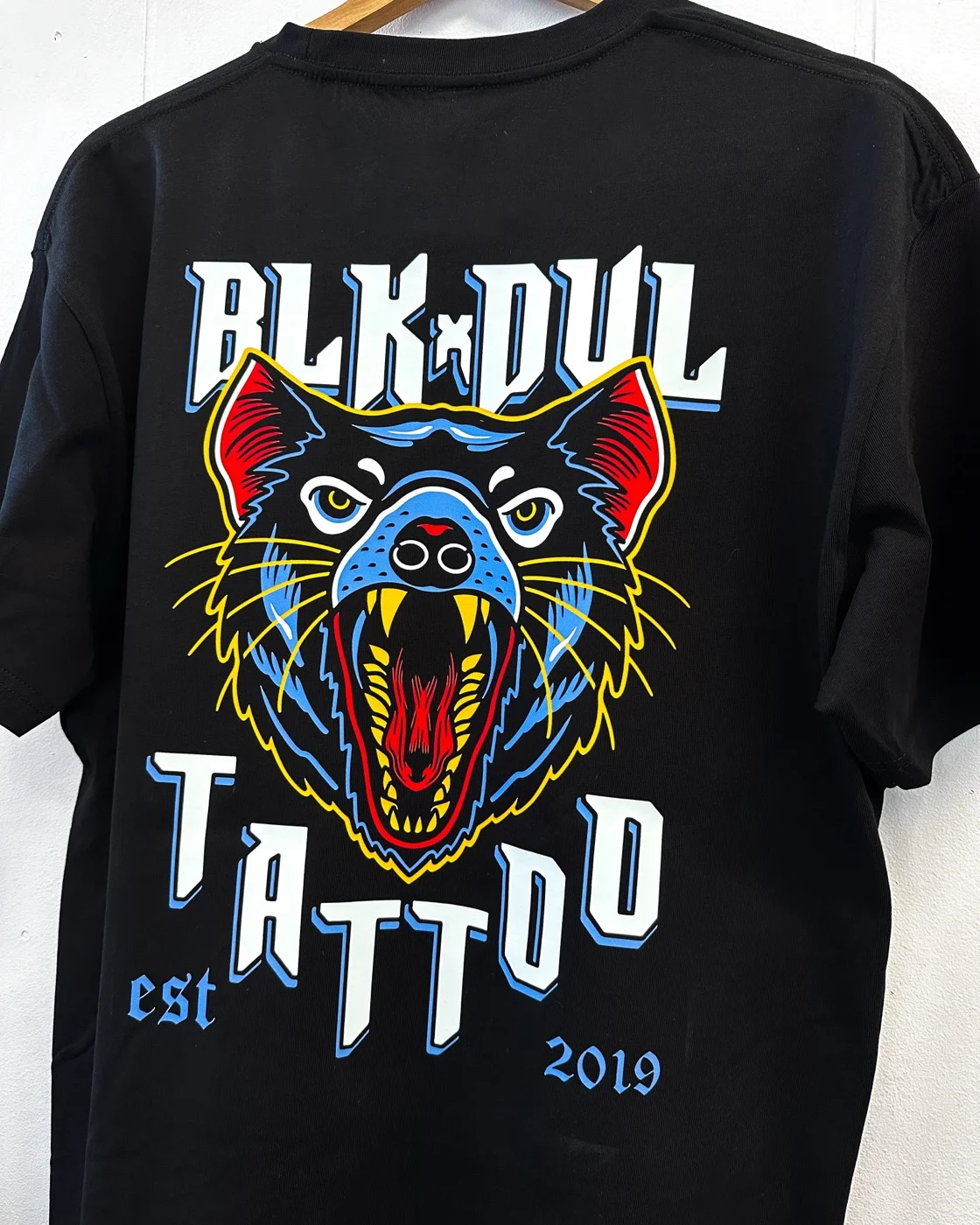 Black Devil Tattoo DTF print tee hung up showing colourful design